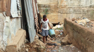 A young woman walks alone in a district in Freetown, going to a water source. Sierra Leone