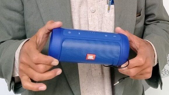 man holding blue speakerbox