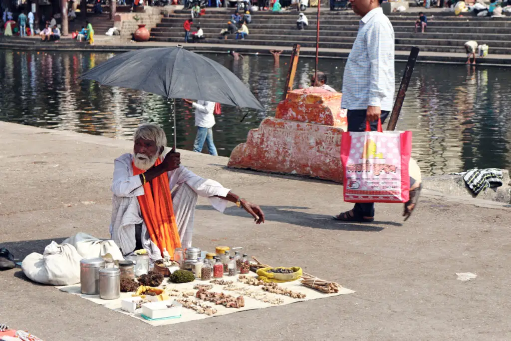 man sells talismans under the shade of an umbrella