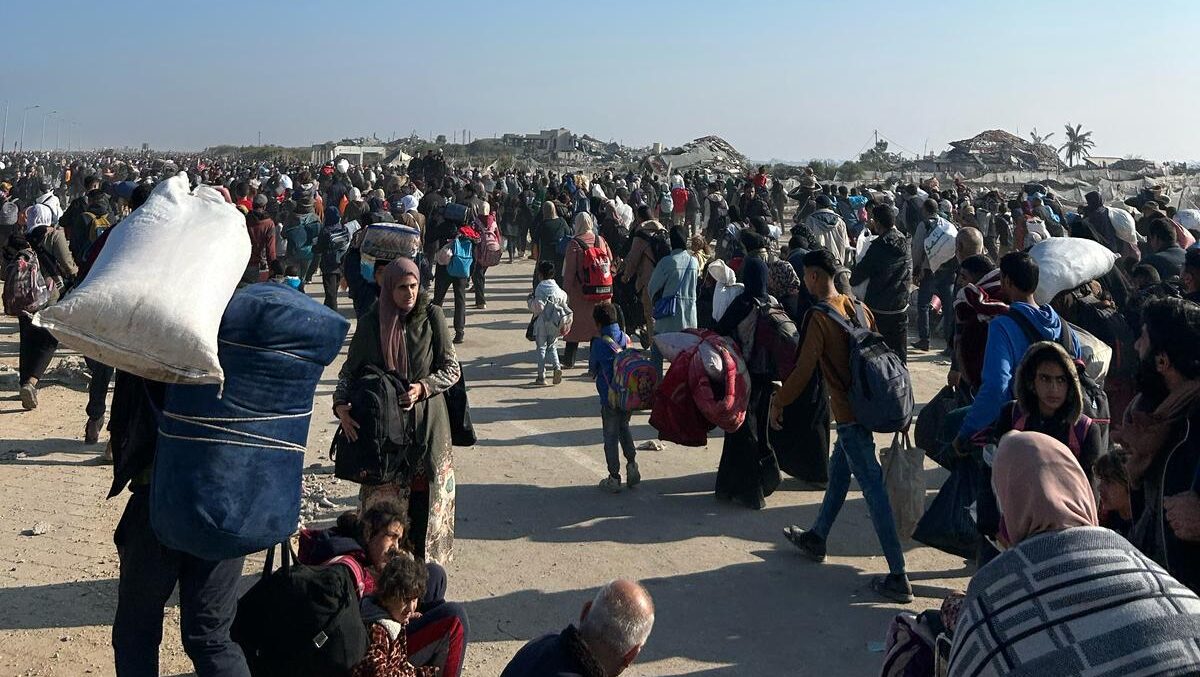 A crowd of Palestinian people walking with bags