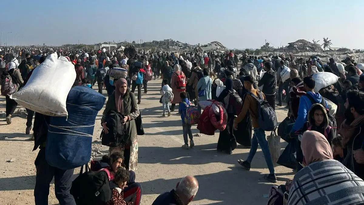 A crowd of Palestinian people walking with bags